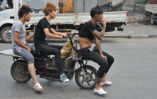 7月15日,在天坛一街上,三名男子共乘一辆改装后的电动车在路上骑行