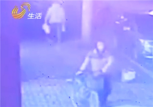 视频监控中朱汇文推着自行车往回走。（视频截图）