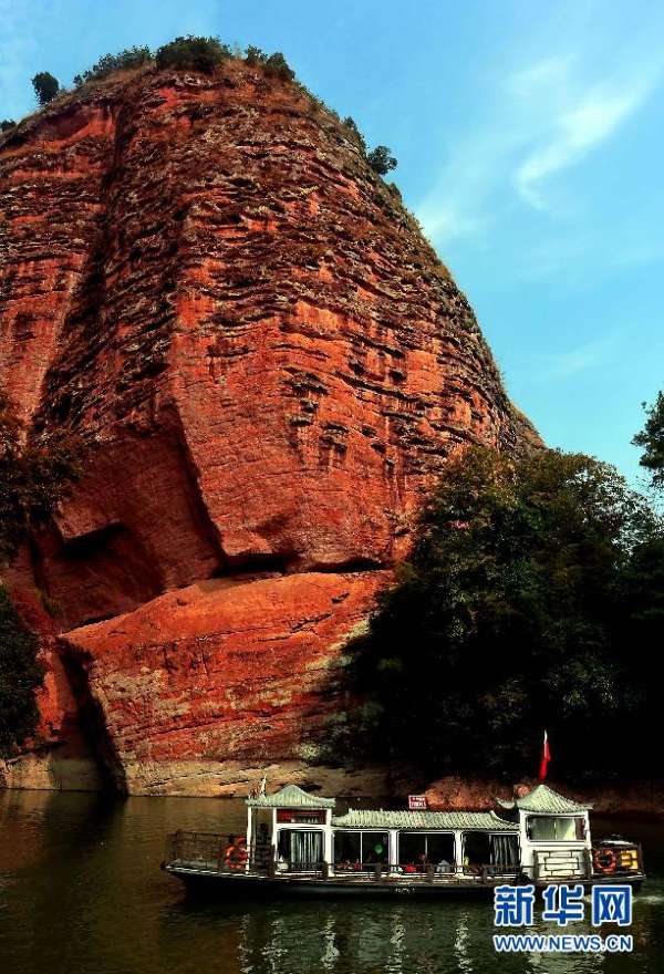 在福建泰宁大金湖景区,一艘游船经过一处丹霞地貌的山峰(2014年10月26