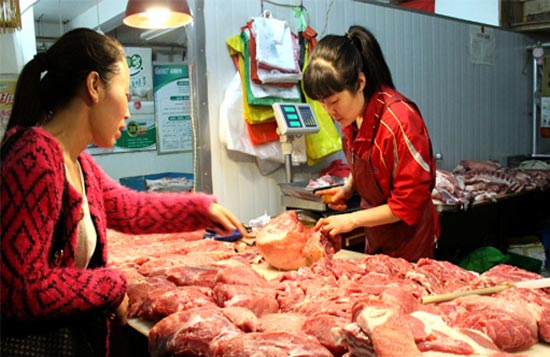 一女士在农贸市场挑选猪肉。