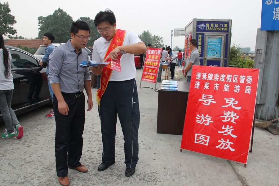 10月3日，在蓬莱市八仙雕塑的志愿者旅游咨询服务点，仙境旅游志愿者们正为来自天津市的几位自驾游客提供旅游咨询服务，得到满意解答的游客们临走时连声致谢。