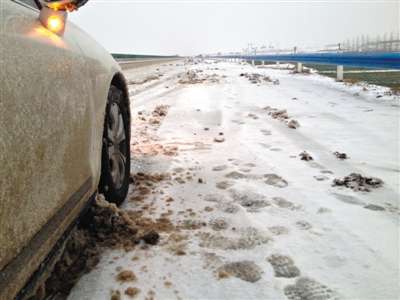 2月5日，S49高速路河南舞钢境内，车轮夹带积雪阻塞在底盘缝隙，行驶一会就需要停车清理。新京报记者吴江摄