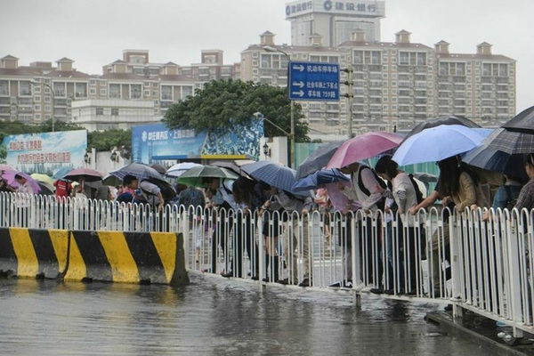 上海暴雨致地铁口积水 行人排队踩护栏 过河