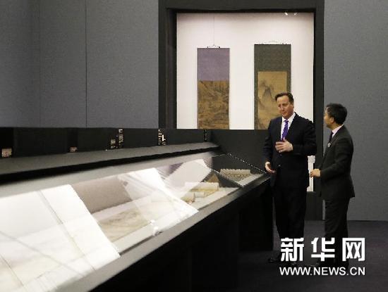 11月28日，在伦敦维多利亚和艾尔伯特博物馆，英国首相卡梅伦（左）聆听中国藏品高级研究员张弘星的介绍。新华网图片 王丽莉 摄