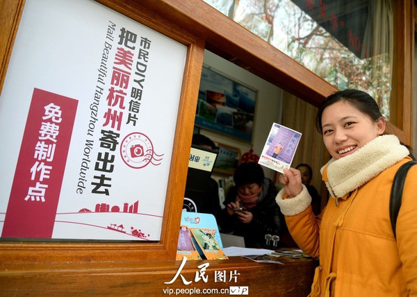 一名游客在杭州曲院风荷DIY明信片免费服务点前展示印有自己照片的DIY明信片。