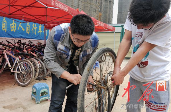 大四学生张少带着学弟在维修旧自行车。