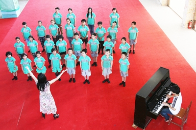 校长康丽在指挥孩子们练习大合唱.