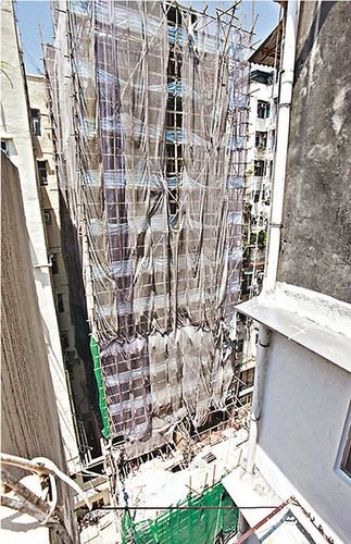 发生男女手牵手跳楼大厦外墙正进行翻新工程。