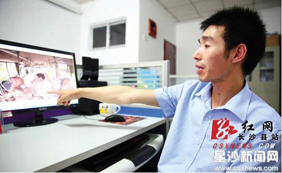 刘飞指着视频，向记者介绍被打时的情形。他脖子上被打的瘀痕还清晰可见。刘晓东 摄