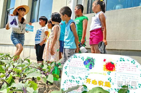 6月24日,一位老师在“开心农场”里为学生们上英语课。