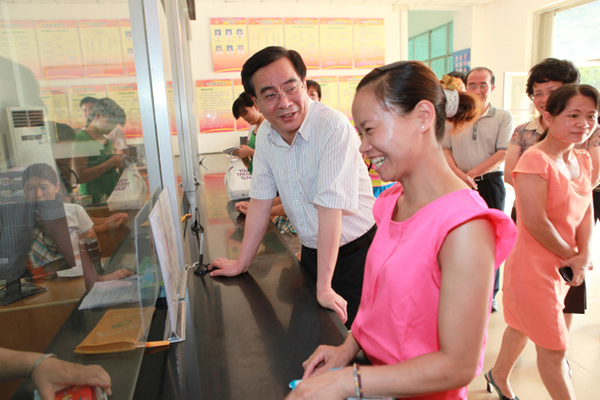 李国坚（左）在阳圩镇政务中心向群众询问办理计生证的情况。