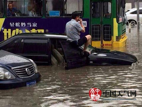 积水淹没私家车，司机攀至车顶避险。