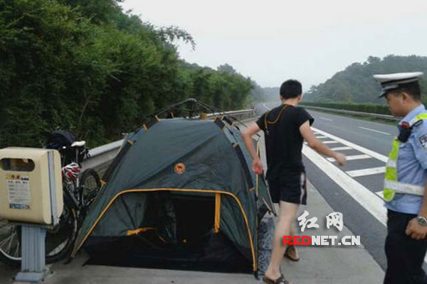 (帐篷内躺着两个年轻小伙，里面的被褥、小风扇、零食、平板电脑一应俱全。)