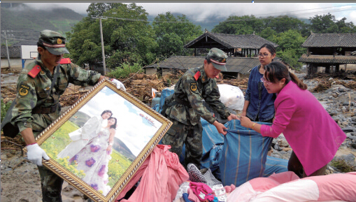 7月11日，在香格里拉县，武警官兵帮助村民转移物资。新华社发