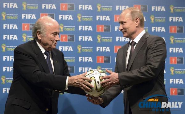 当地时间7月13日，巴西里约热内卢，俄罗斯总统普京从国际足联主席布拉特手中接过足球，这是世界杯举办权交接仪式的一部分。（路透社）