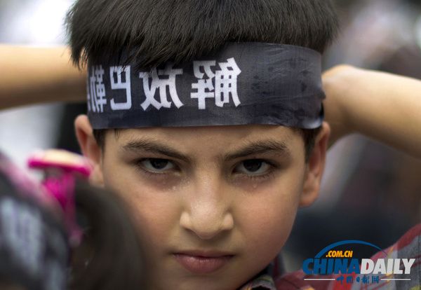 2014年7月18日，中国北京，伊拉克小孩戴头巾，上面写着“解放巴勒斯坦”。当天，多国民众在巴勒斯坦驻北京大使馆外游行，抗议以色列攻击加沙地带。（图片来源：东方IC）
