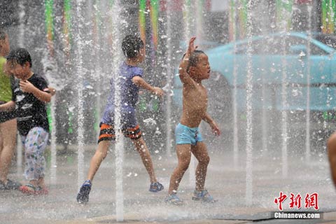 7月20日,北京天气炎热,孩子们在喷泉中嬉水纳凉。