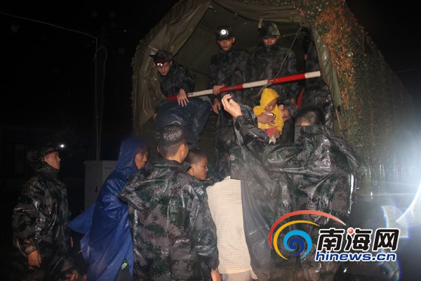 海南军区某炮兵团的官兵冒雨趟着一米多深的水进入厂区转移被困群众。(军区供图)