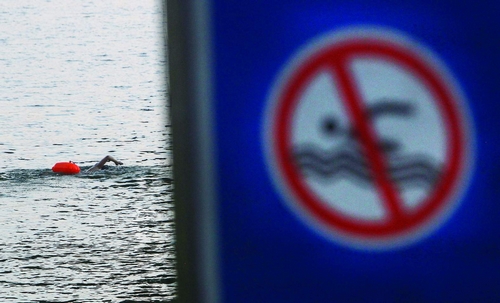 7月29日，猴子石大桥，江边虽有禁止游泳的标识，市民依然在水里游泳。图/记者华剑