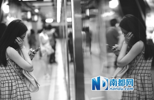 ↑一位女乘客在屏蔽门前低头看手机。