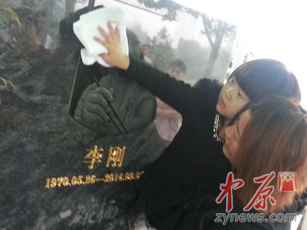 　　李刚的女儿被妈妈抱起，帮爸爸擦拭墓碑