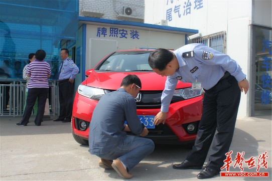 在长沙车管所城南分所，所长廖钢正指导师傅给一辆新车装车牌。