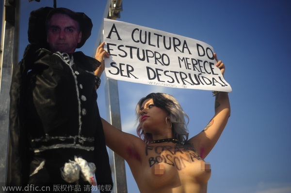 当地时间2014年12月19日，巴西里约，2名Bastardxs女权主义运动成员裸上身将巴西国会议员Jair Bolsonaro的人像吊起来，抗议其强奸妇女。（图片来源：东方IC）