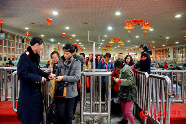 图为:襄阳车站候车大厅的除夕夜,客运员谢北华和客运值班员黄英正在为旅客放行。