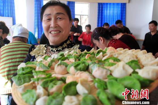 一位大妈在展示居民们包的饺子。　曹新加　摄