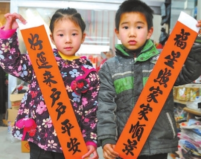 两位小朋友展示一对白额春联。