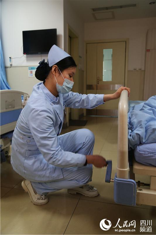 怀孕22周的护士肖燕为病人调节病床（熊文瑶 摄）