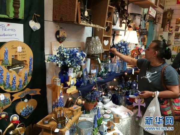 游客在一家摆满以蓝帽花为题制作的手工艺品。新华网发 张永兴 摄