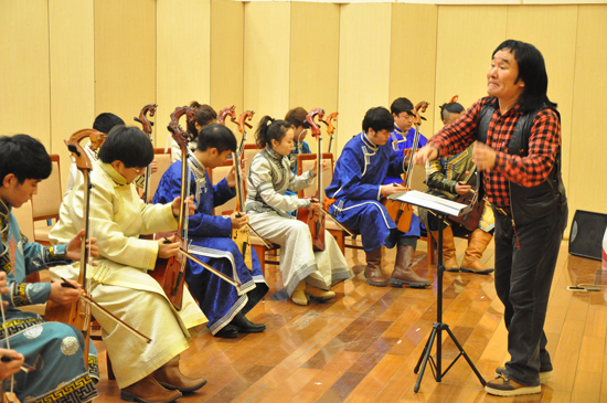 齐·宝力高在指挥学生演奏马头琴。（资料图片）