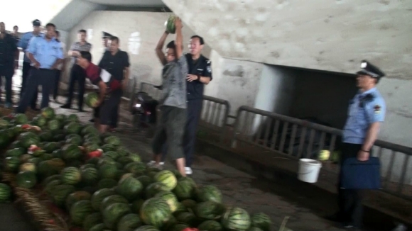 现场视频显示，摊贩自己搬起西瓜砸向地面