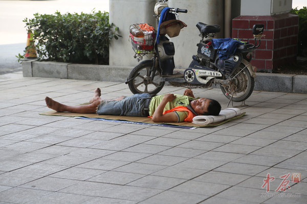 郑州高铁站旁，一名环卫工在高架桥下的阴凉处午睡