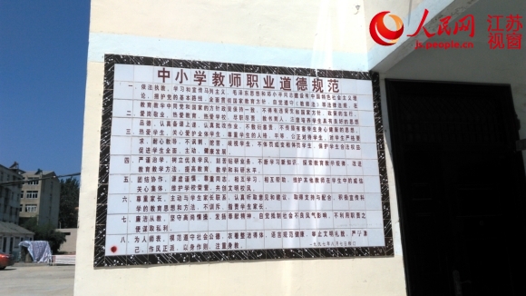悬挂在何桥镇中心中学办公楼前的教师职业道德规范，白底黑字十分醒目。