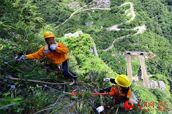 在烈日的炙烤下，巡山工的衣服被汗水浸湿，不停地擦着汗水
