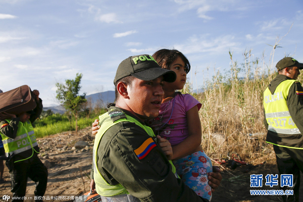 当地时间2015年8月27日,委内瑞拉San Antonio,哥伦比亚警察抱着一名女孩返国。(图片来源:CFP)