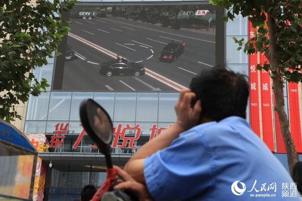 一位电动车司机将电动车停下，坐在车上观看阅兵仪式。杜旭涛 摄