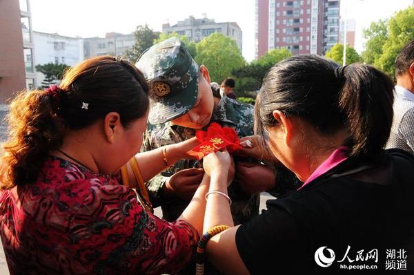 图为长辈为新兵戴上光荣花时的情景