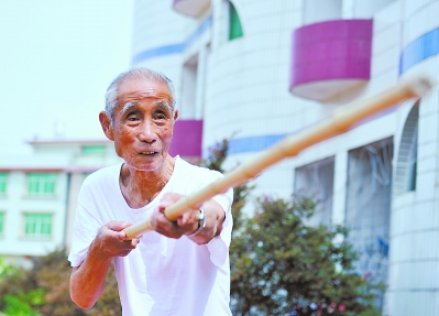 老人拿起一根竹子当作“刺刀”，双手紧握“刺刀”，演示起那段抗战中最深的记忆。