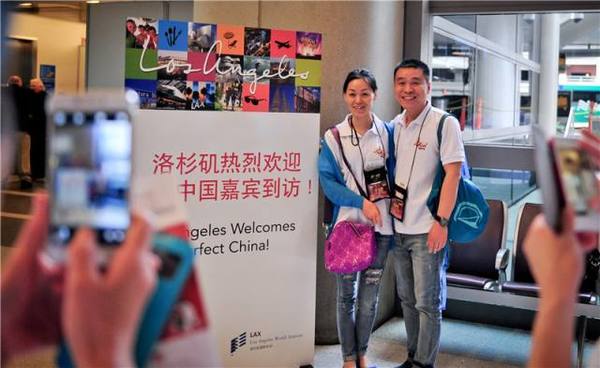 资料图:在美国洛杉矶国际机场,两名中国旅游团成员与洛杉矶会议及旅游局打出的欢迎标语牌合影留念。新华社发