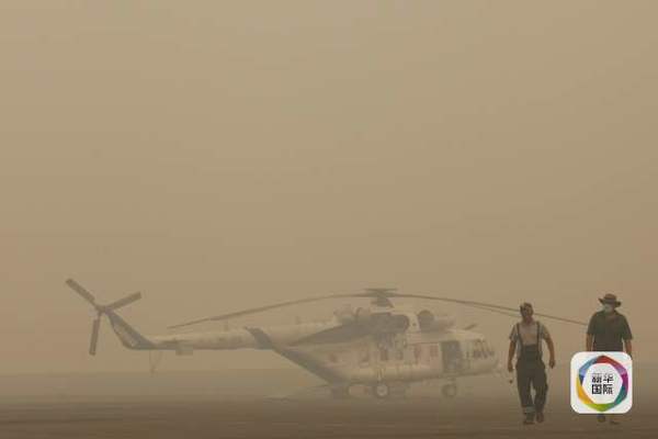 　　图为烟霾中一架参与灭火的直升机。（图片来源：新华/法新）