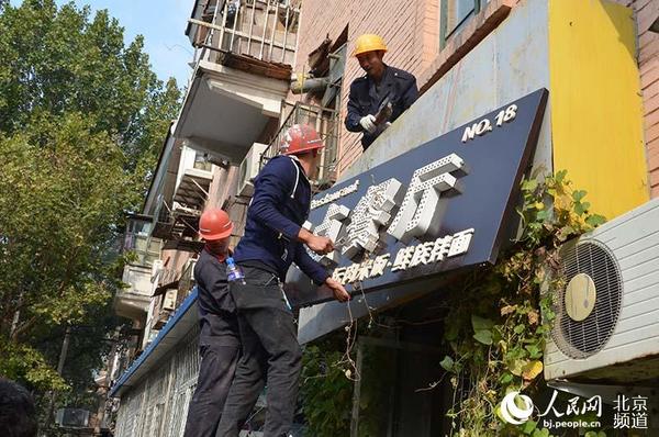 施工人员拆除违建商户招牌。 人民网 陈一诺摄
