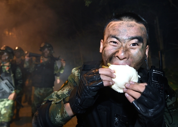 10月25日,武警特战队员张茂在夜间奔袭中抓紧吃干粮补充体力。新华社记者 陈飞 摄