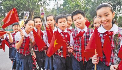 越南少年儿童挥舞两国国旗迎接习近平总书记。