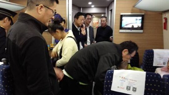 　　▲10月25日，胡大一(俯身者)在高铁上救治一名突发心脏病患者。
