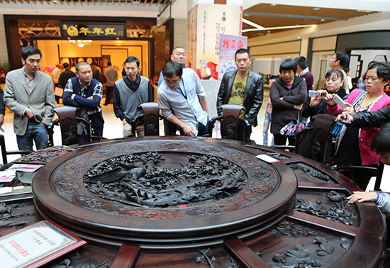 木雕爱好者在博览会上鉴赏木雕家具产品（人民网 张桂贵 摄）