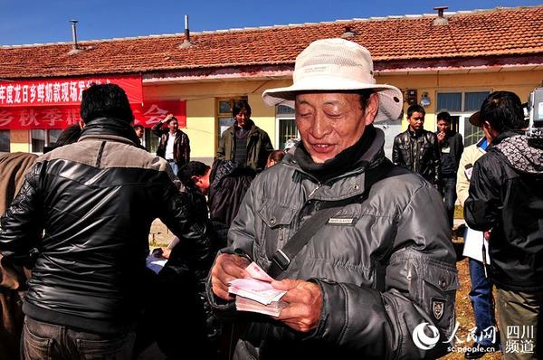 牧民出售鲜奶后领取鲜奶款。（图片由红原县委宣传部提供）