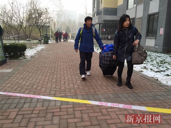 警方在事发小区单元楼门口设置警戒线，该单元部分居民正在拉着行李离开受损住所。新京报记者吴江摄